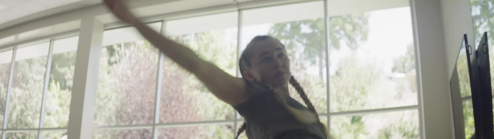 Girl with braided hair dances in a big gym during daylight