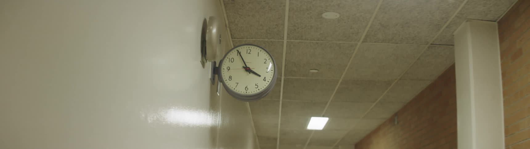 A clock protrudes from the wall in a hallway
