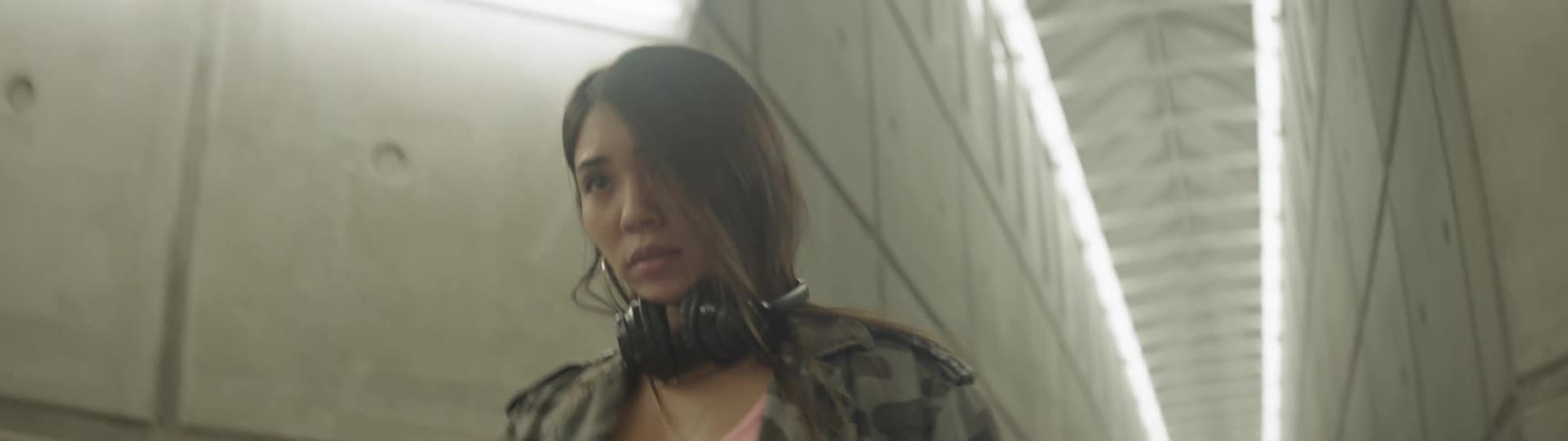 A woman is walking in a tunnel and putting headphones on