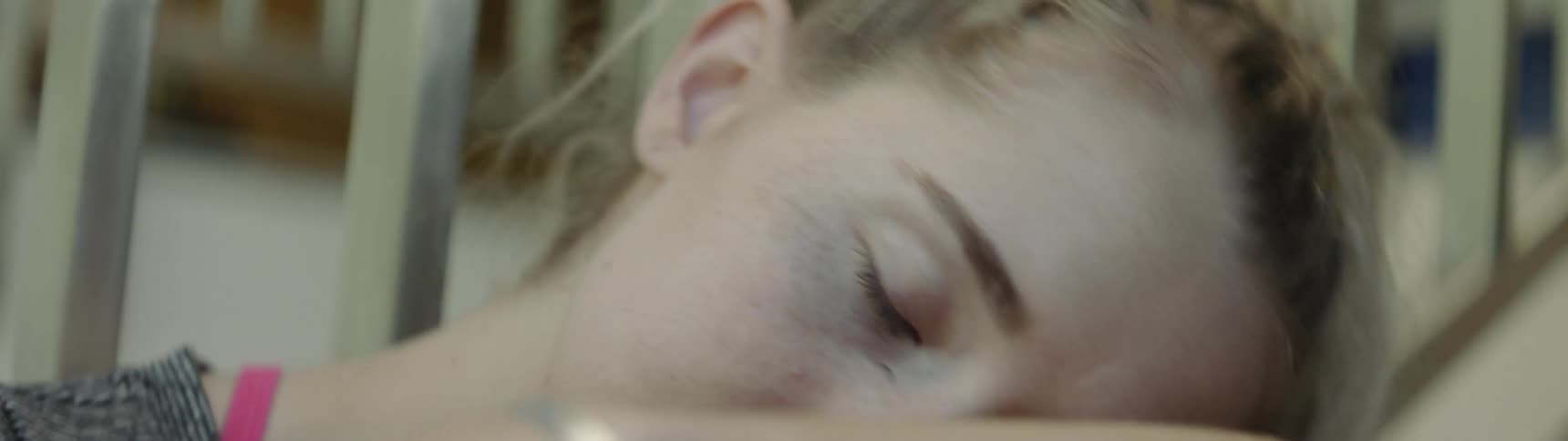 A girl sitting near a stairwell looks up then drops her head onto her arms