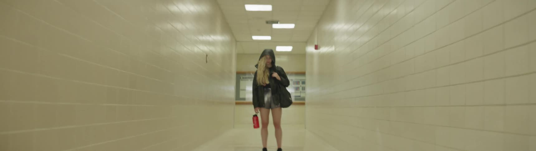 A young woman stands in a long hallway