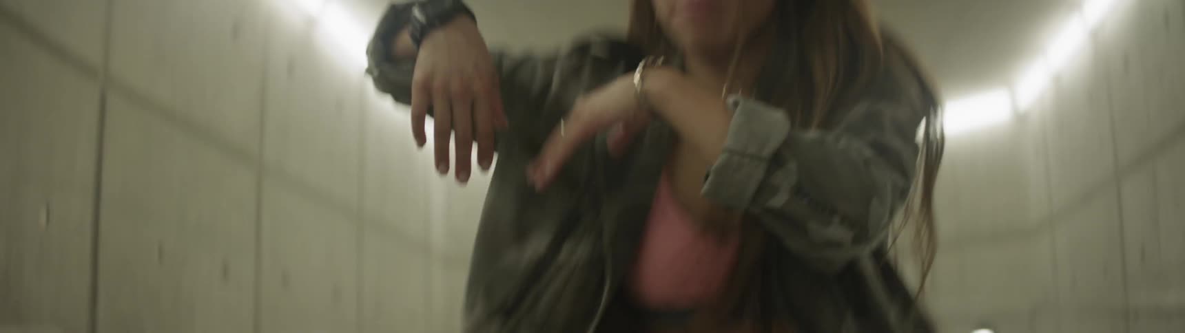 Asian girl wearing headphones dances in underground hall