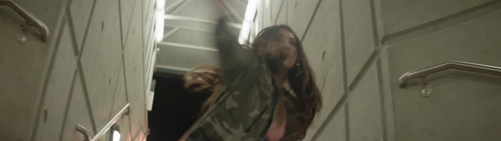A woman is dancing as she climbs up the steps in the tunnel