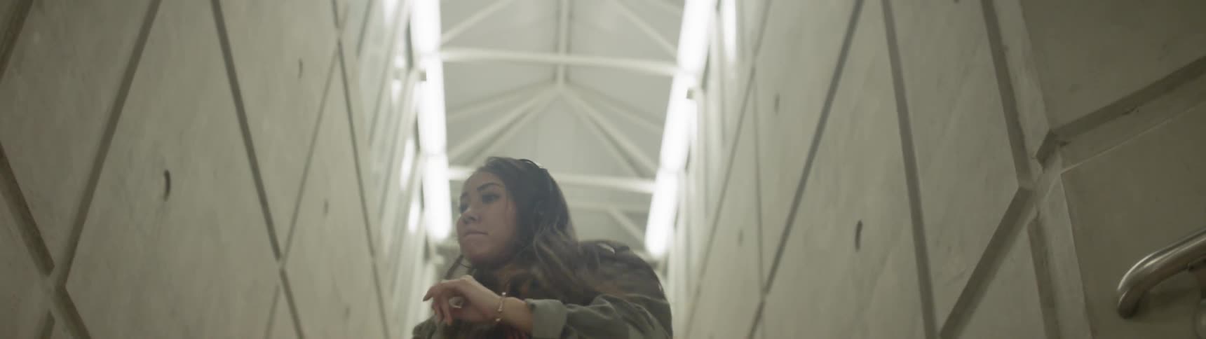 A woman dances in a well lit stairwell