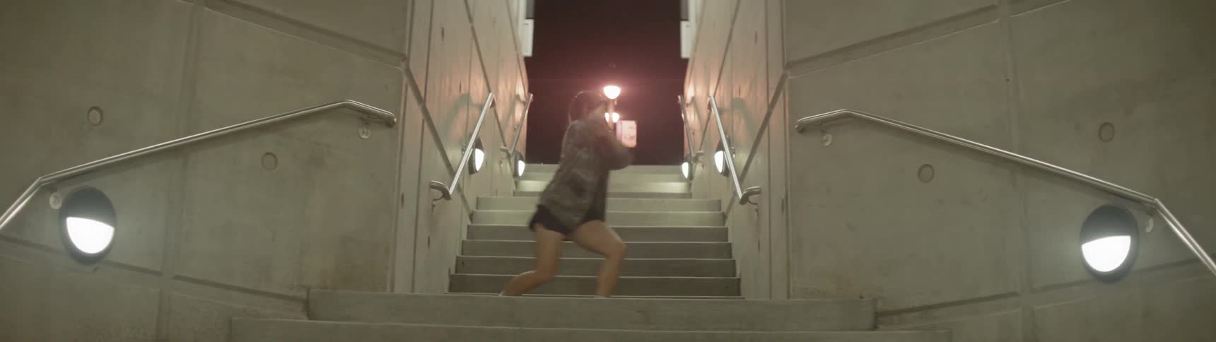 Woman dancing on the entrance stairs of a subway station at night