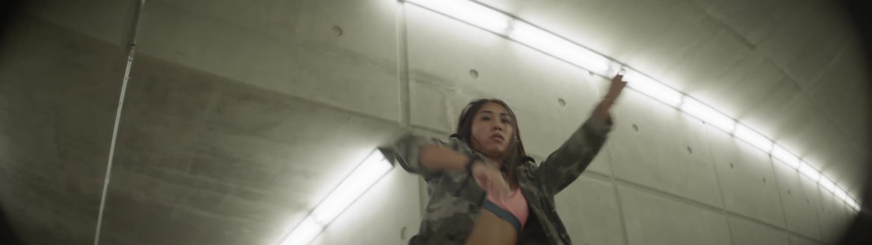 A woman is dancing indoors while wearing headphones