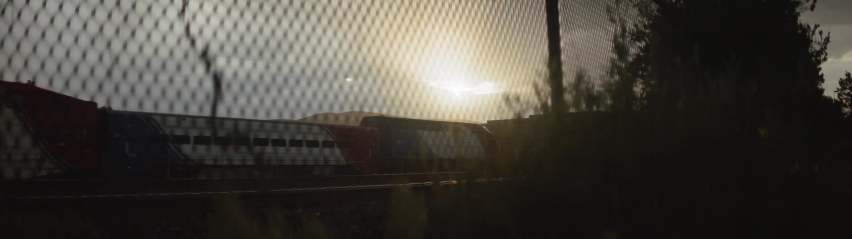 A train passes by a fence in a rural area