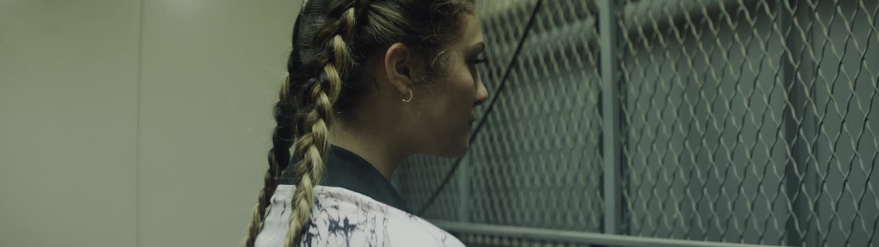 A young woman waits in front of a gated elevator