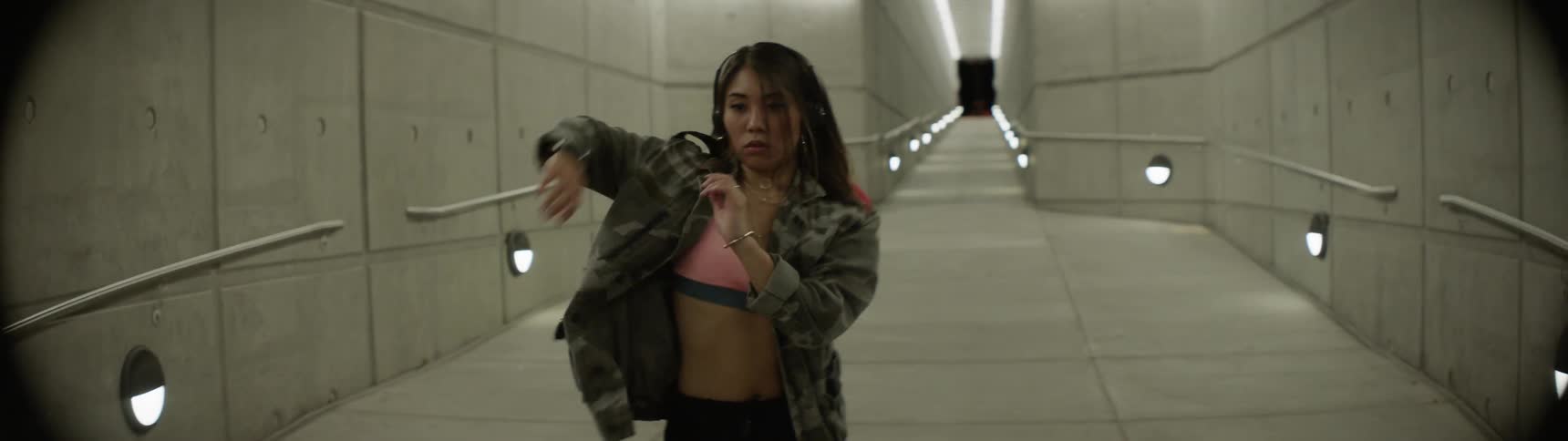 An asian teenager practices her dance moves in an empty hallway