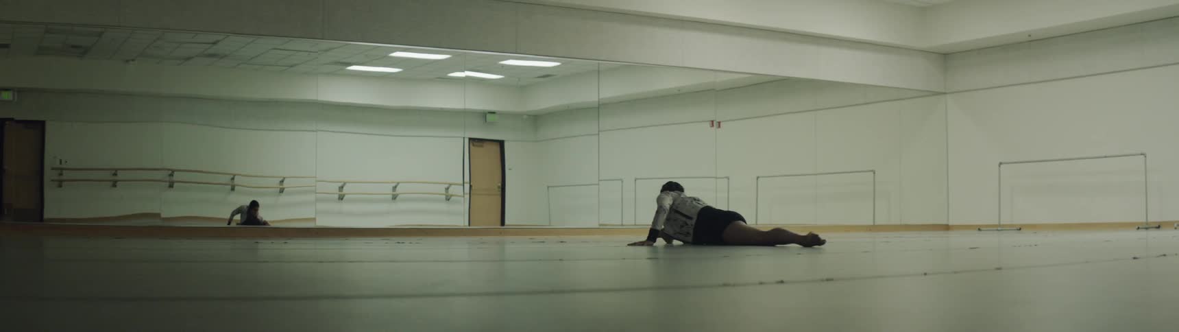 A woman does the splits and stretches in a studio
