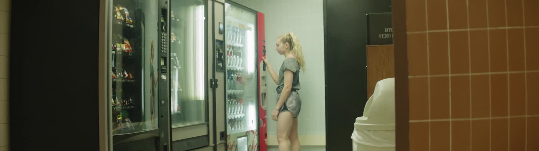 A girl stops at a vending machine to make a purchase