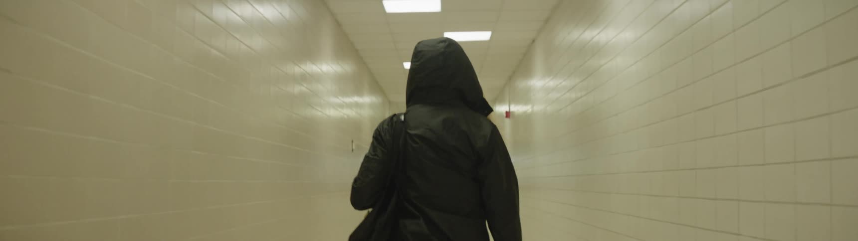 Person walks down hallway in hooded coat
