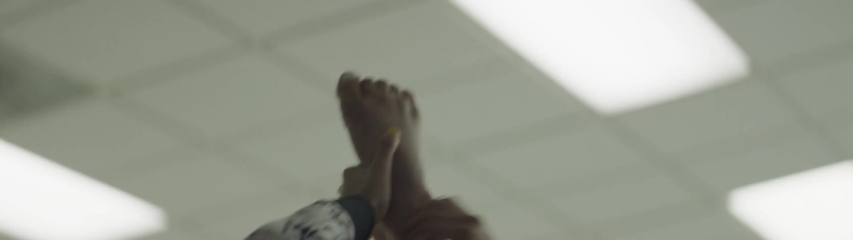 A female dancer with incredibly good control of her body raises her right leg above her head while standing and holds it there for several second before lowering it