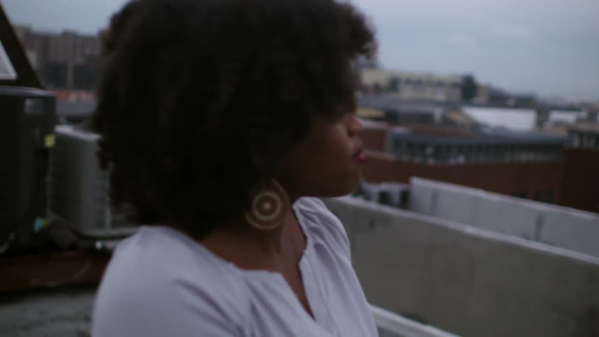 A woman stands chilly on a city rooftop