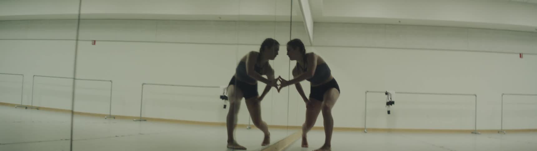 A woman is looking in a mirror and dancing