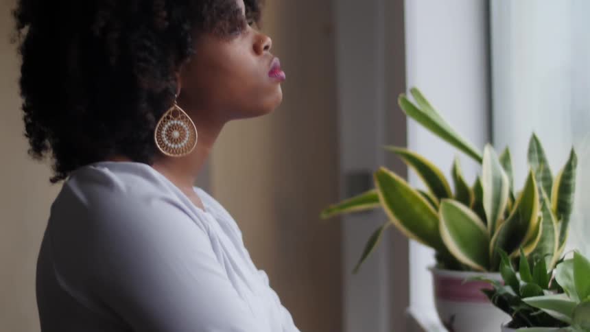 A woman leans on a windowsill as she looks out a window