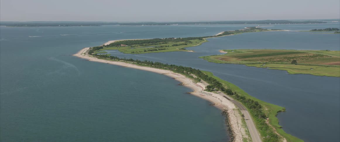 A narrow road runs along a strip of dry land the very edge of a coastal landscape