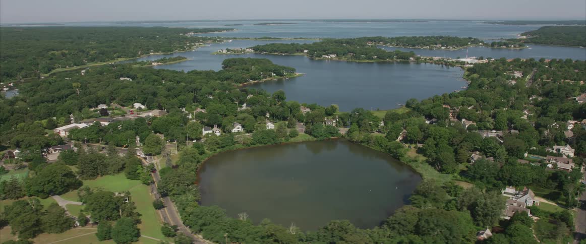 An aerial view of a neighborhood surrounded by trees and lakes