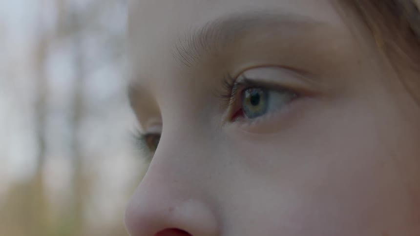 A girl blinks her eyes on a sunny day