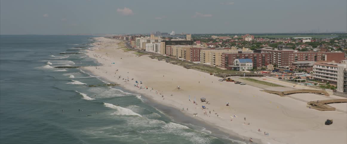 A beach many people and a large city in the background