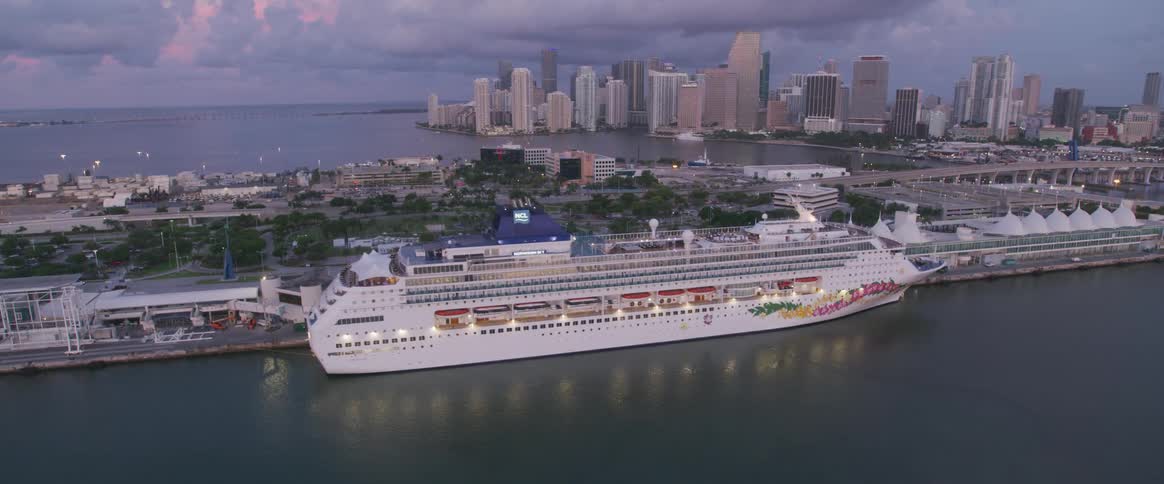A cruise ship is in port with the city of miami skyline on the horizon