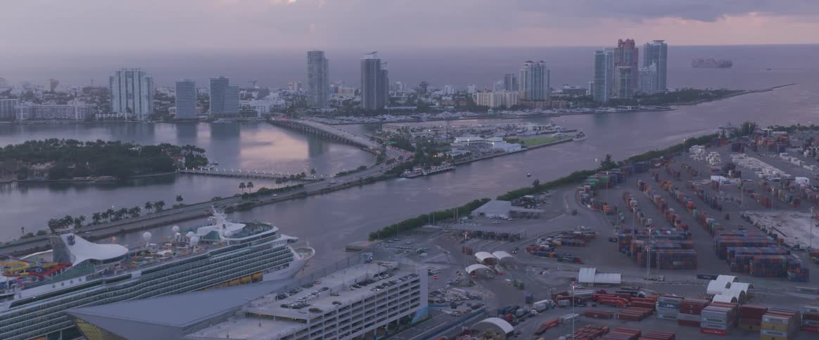 A huge cruise liner is seen dock along the waterfront of a city with numerous skyscrapers