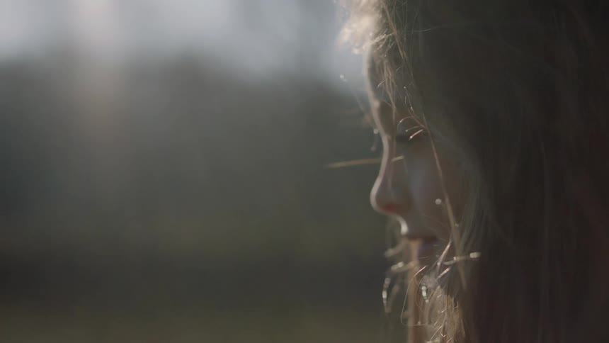 A young girl stands outside smiling on a sunny day