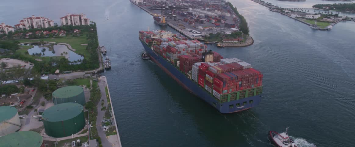 Freight ship and refineries near docks with city on horizon