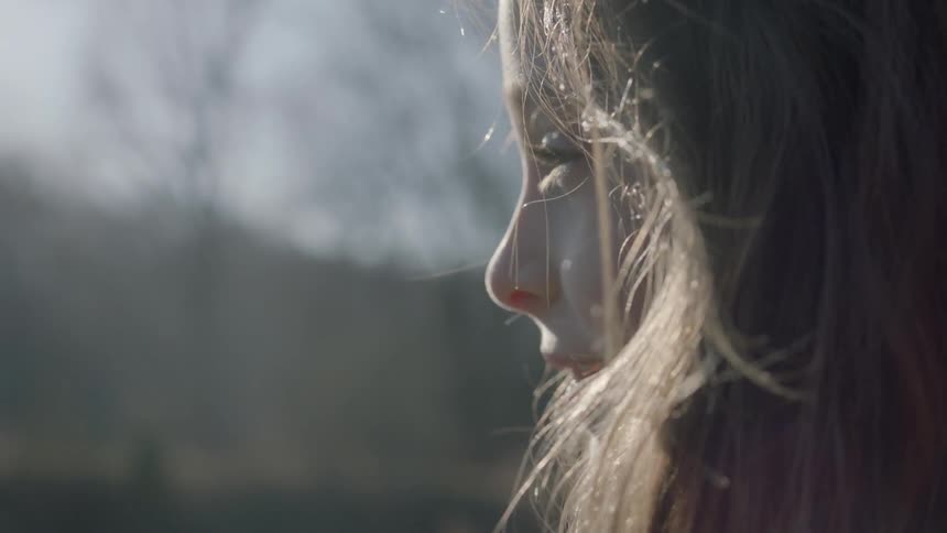 A girl smiling as she looks around outside on a sunny day