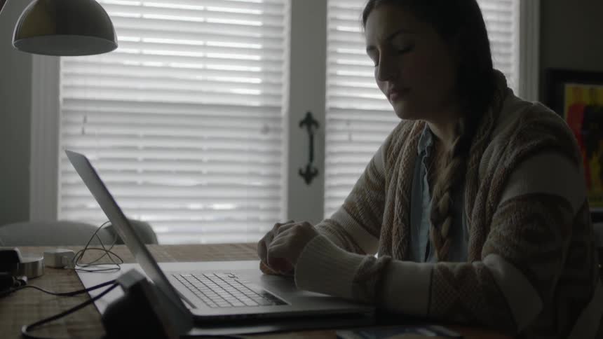 A woman sits at a desk working on her laptop