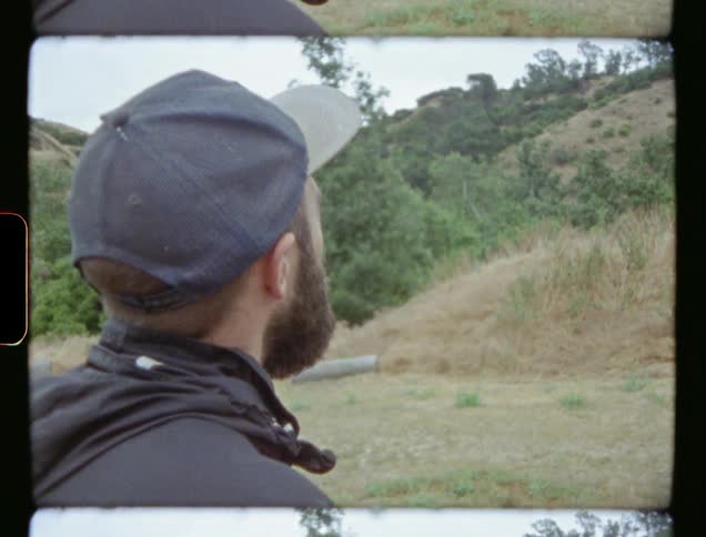 Man stands outdoors looking towards a hill
