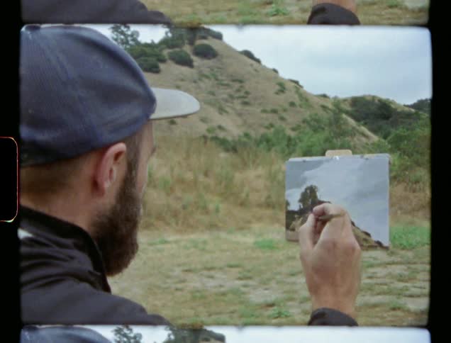 A man paints a picture of scenery he's looking at