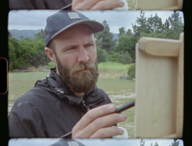 A man paints outside on an easel