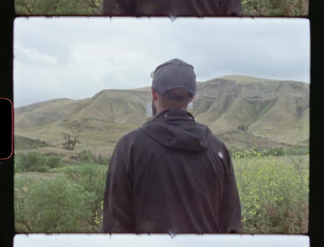 A man looks at a picture of a mountain while standing in front of that mountain