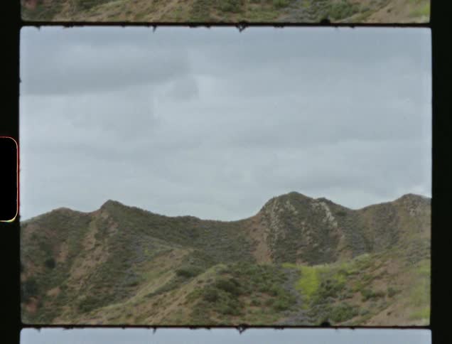 Old film of a mountain covered with grass