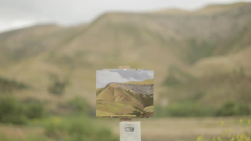 A man reads a sign for a mountain range that's in front of him