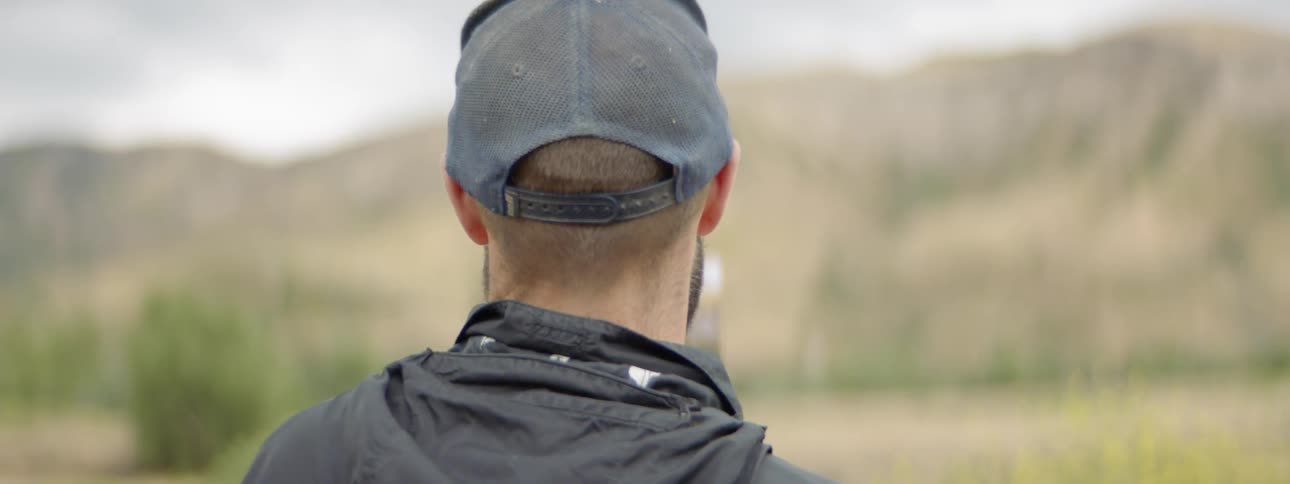 Man wearing cap paints the picture of landscape with mountain during daylight