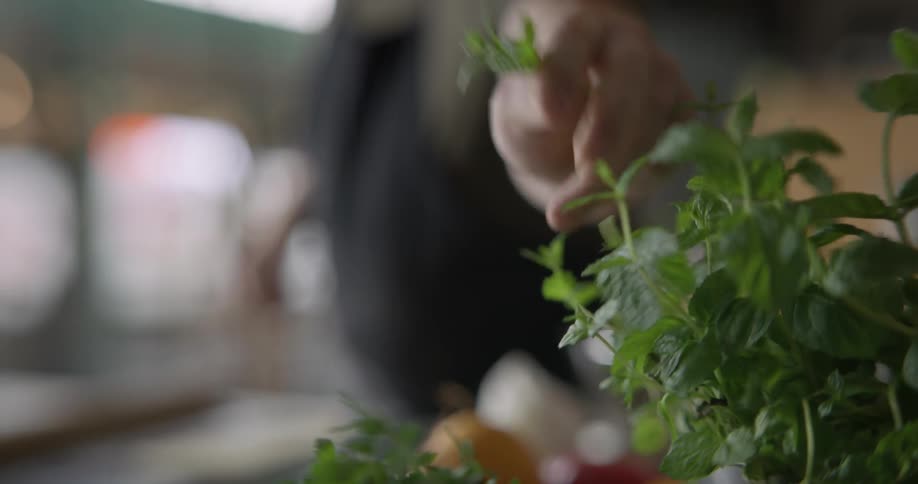 A man's hand grabs some fresh herbs in slow motion.