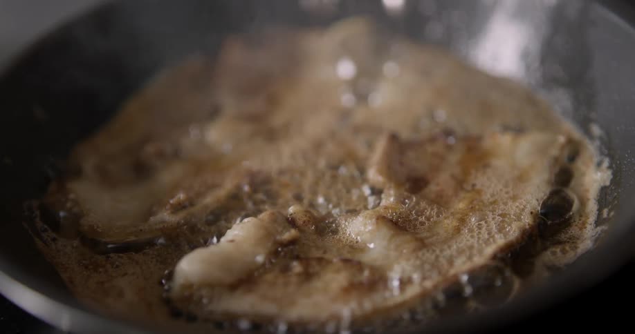 Bacon and eggs sizzle in a steamy frying pan.