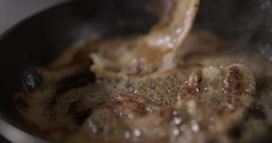 Bacon sizzles on skillet as fork stirs.