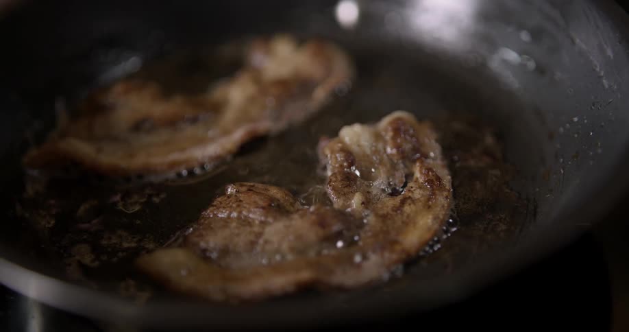 Bacon sizzling in the pan in close-up slow motion.