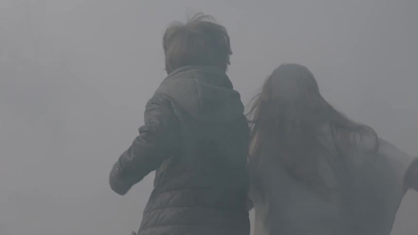 Two children run out of a smokey woods