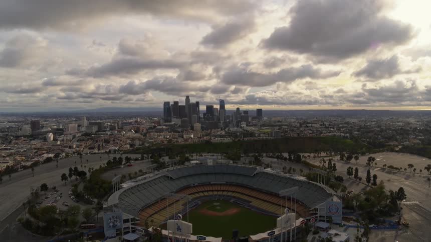 Drone footage captures the spectacular view of the city skyline and baseball stadium on a sunny afternoon in Los Angeles.