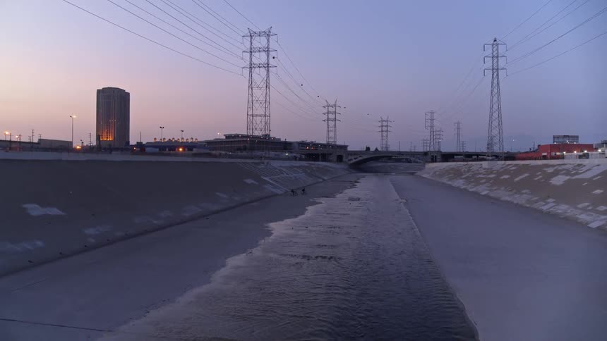 People walking and riding bikes through a culvert with water