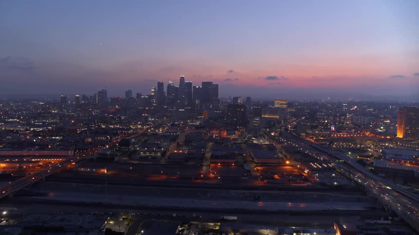 The sky is getting dark as the sun sets behind the city in the distance