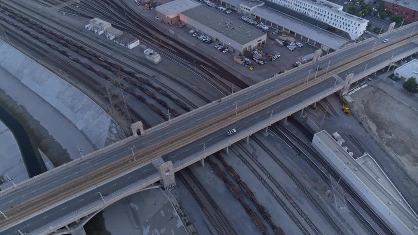 Cars drive across a long bridge crossing train tracks