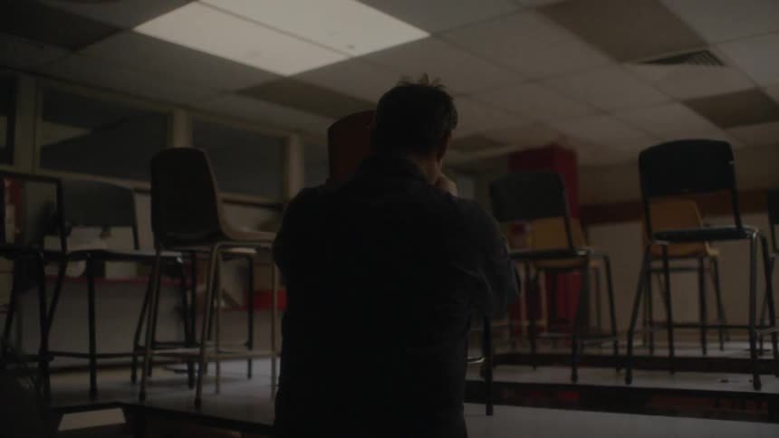 A teacher stacking chairs in a classroom