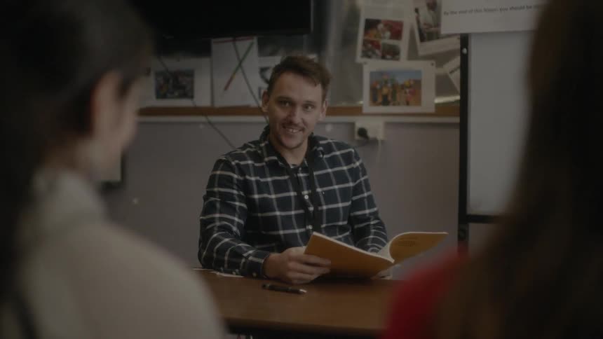 A man sitting behind a desk in conversation with two women about a book