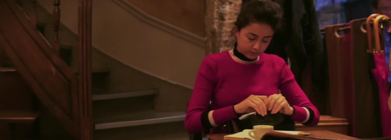 An indian woman looks for money in her bag as a waiter comes to pick up the check