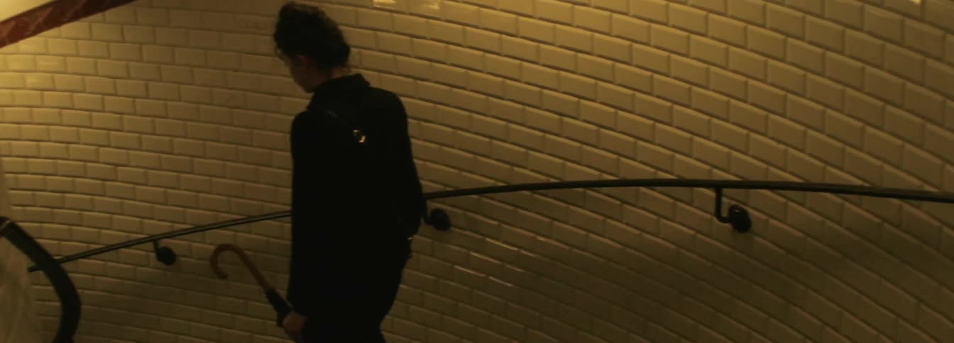 A woman descending a dim spiral staircase